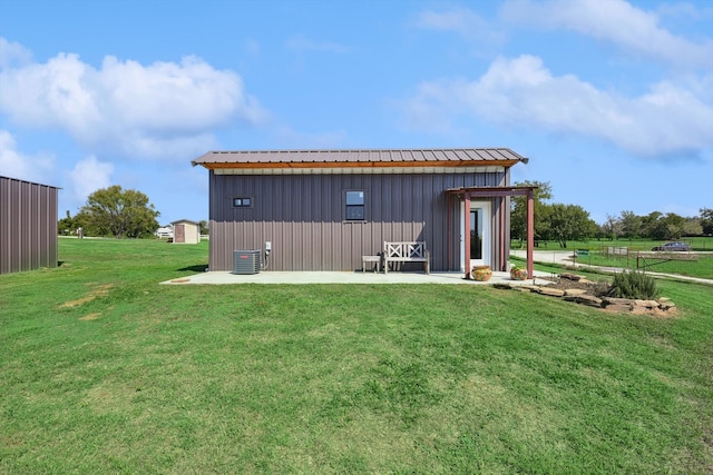 view of outdoor structure featuring central AC and a yard