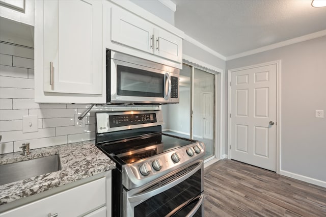 kitchen with wood-type flooring, white cabinetry, light stone countertops, and stainless steel appliances