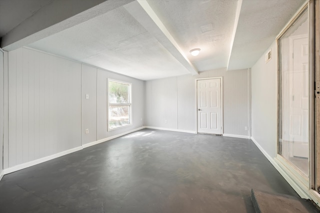 unfurnished room featuring a textured ceiling and beam ceiling