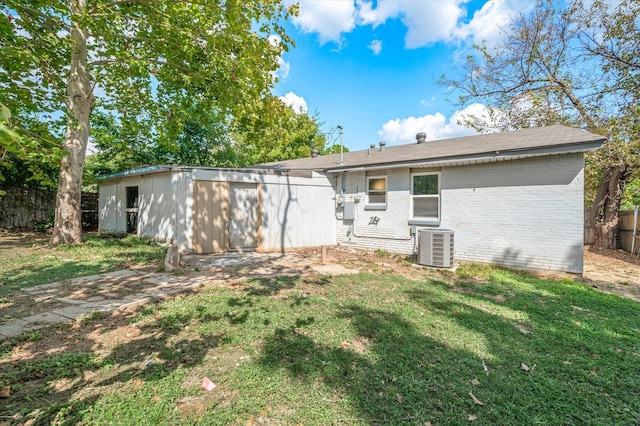 back of house with a lawn, a storage shed, and central air condition unit