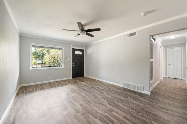 spare room featuring ornamental molding, wood-type flooring, ceiling fan, and a textured ceiling