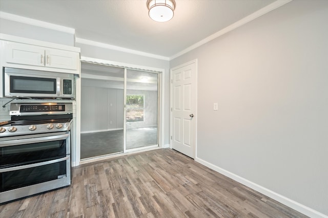 kitchen with light hardwood / wood-style flooring, stainless steel appliances, ornamental molding, and white cabinetry