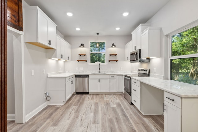 kitchen featuring white cabinets, sink, hanging light fixtures, light hardwood / wood-style flooring, and stainless steel appliances