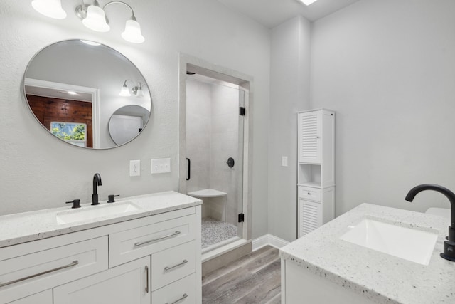 bathroom with wood-type flooring, vanity, and a shower with door