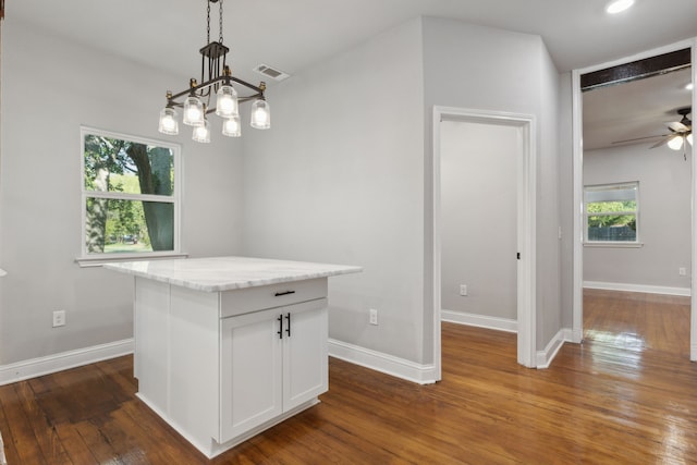 unfurnished dining area with plenty of natural light, ceiling fan with notable chandelier, and dark hardwood / wood-style floors