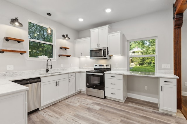 kitchen with appliances with stainless steel finishes, light hardwood / wood-style floors, white cabinetry, and sink