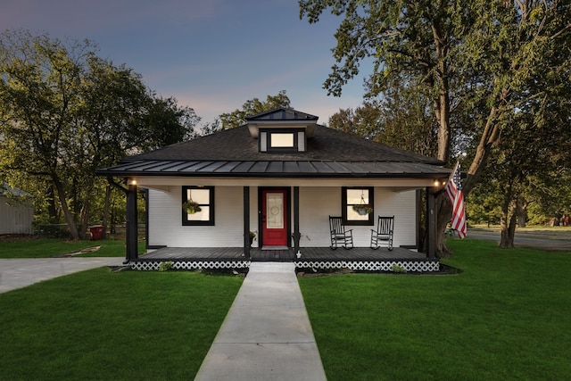 view of front of property with covered porch and a yard