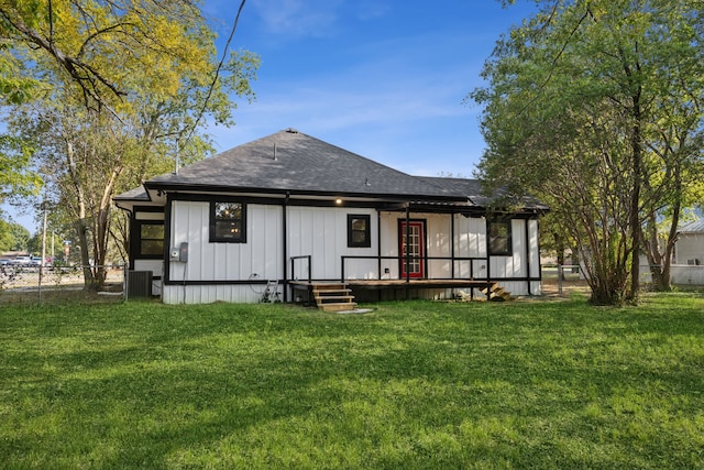 back of property with central air condition unit and a lawn