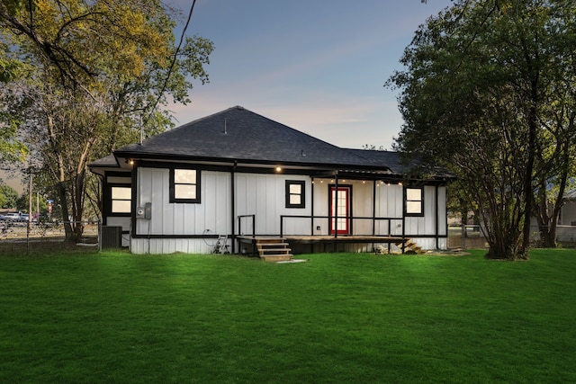 back house at dusk featuring central air condition unit and a yard