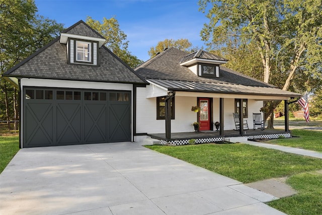 view of front of home featuring covered porch, a garage, and a front yard