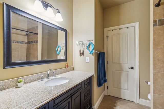 bathroom with a tile shower, vanity, tile patterned flooring, and toilet