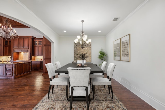 dining space with ornamental molding, a notable chandelier, and dark wood-type flooring