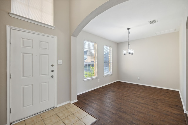 foyer entrance featuring wood-type flooring and an inviting chandelier