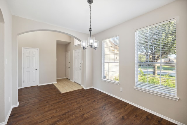 empty room with hardwood / wood-style floors and an inviting chandelier