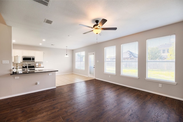 unfurnished living room with hardwood / wood-style floors, a textured ceiling, ceiling fan, and sink