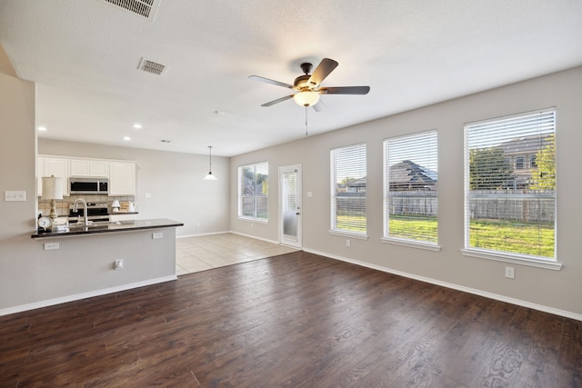 unfurnished living room with hardwood / wood-style floors, ceiling fan, plenty of natural light, and sink