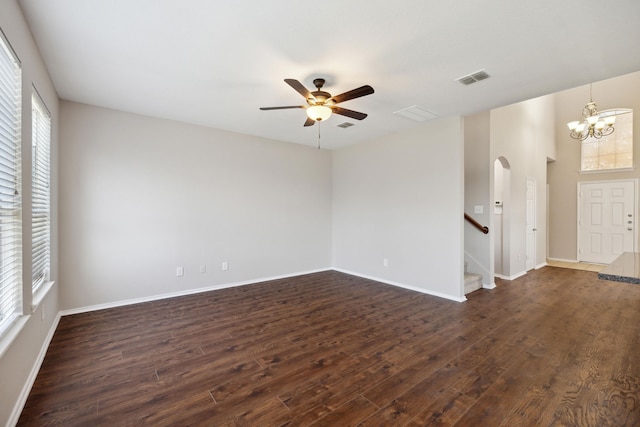 empty room with a wealth of natural light, dark hardwood / wood-style flooring, and ceiling fan with notable chandelier