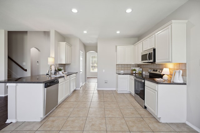 kitchen featuring kitchen peninsula, white cabinets, light tile patterned floors, and appliances with stainless steel finishes