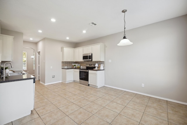 kitchen featuring sink, tasteful backsplash, light tile patterned flooring, white cabinets, and appliances with stainless steel finishes