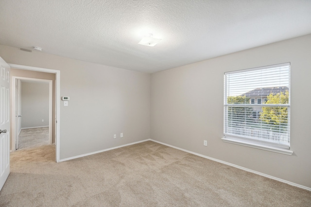 empty room with light colored carpet and a textured ceiling