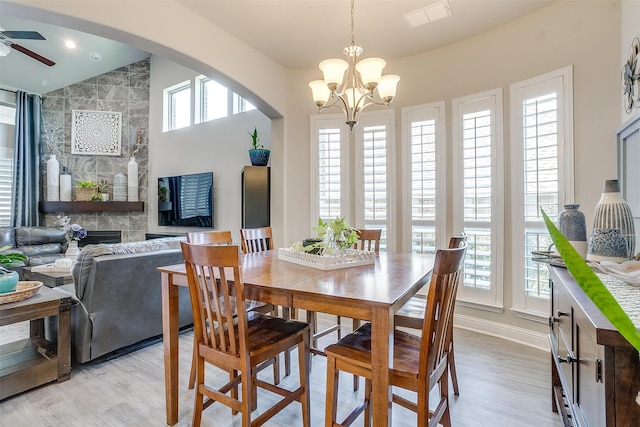 dining space featuring a healthy amount of sunlight, ceiling fan with notable chandelier, and a fireplace