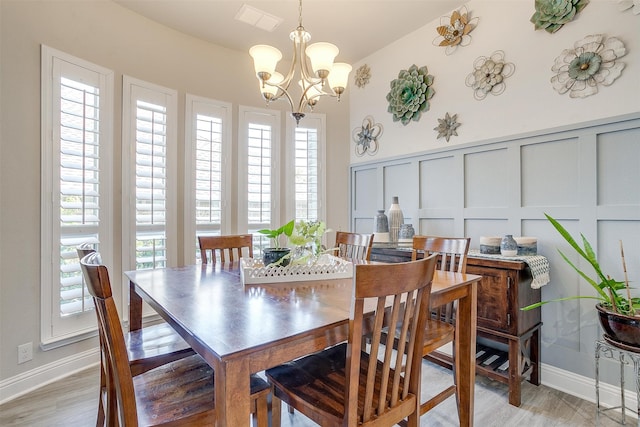 dining space with light hardwood / wood-style floors, vaulted ceiling, and a chandelier