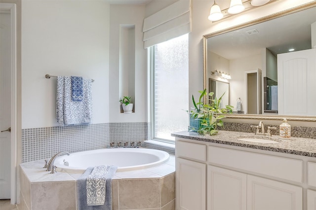 bathroom featuring vanity and tiled bath