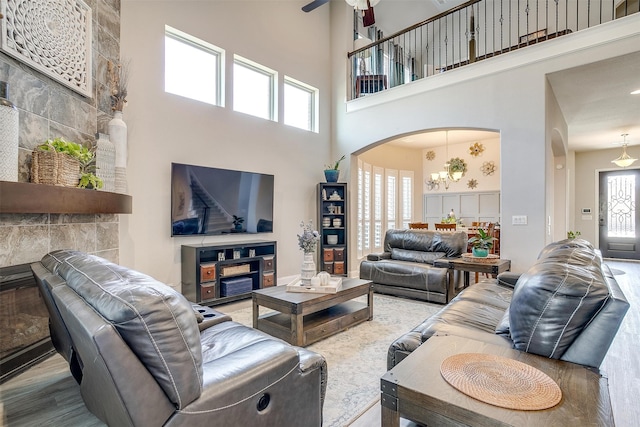 living room with ceiling fan with notable chandelier, a towering ceiling, and hardwood / wood-style floors