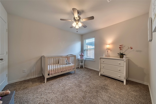 carpeted bedroom featuring ceiling fan and a nursery area