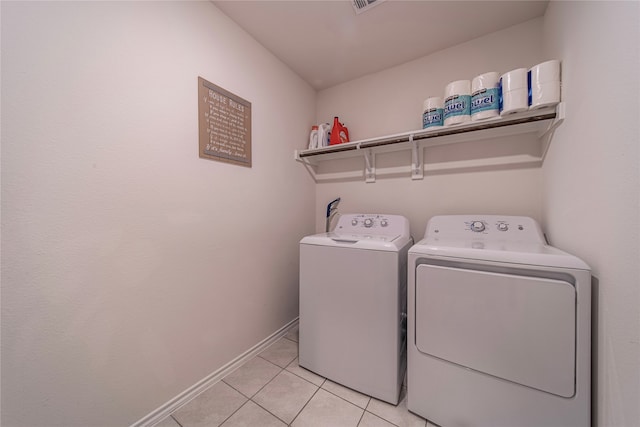 clothes washing area with light tile patterned floors and washer and dryer