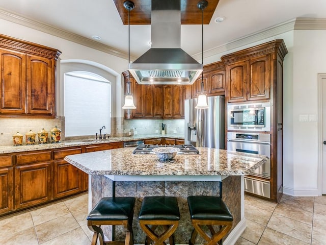 kitchen with a center island, light stone counters, decorative light fixtures, island range hood, and appliances with stainless steel finishes