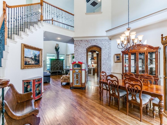 dining area featuring hardwood / wood-style floors, a notable chandelier, and a towering ceiling