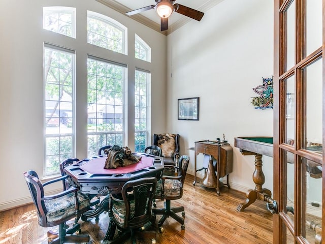 dining area featuring a towering ceiling, crown molding, light hardwood / wood-style flooring, and ceiling fan