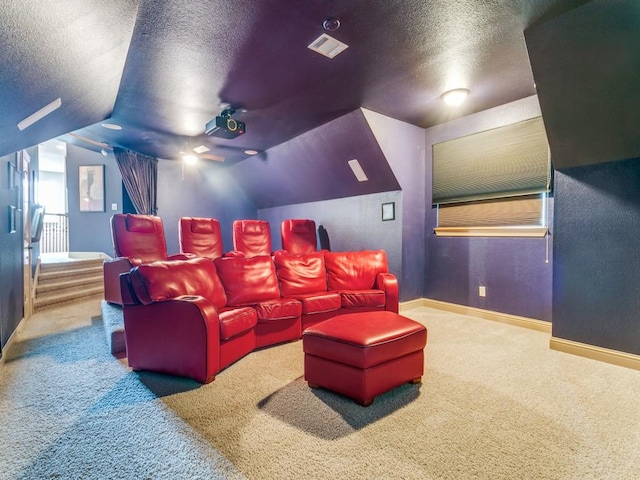 carpeted cinema room with a textured ceiling and vaulted ceiling