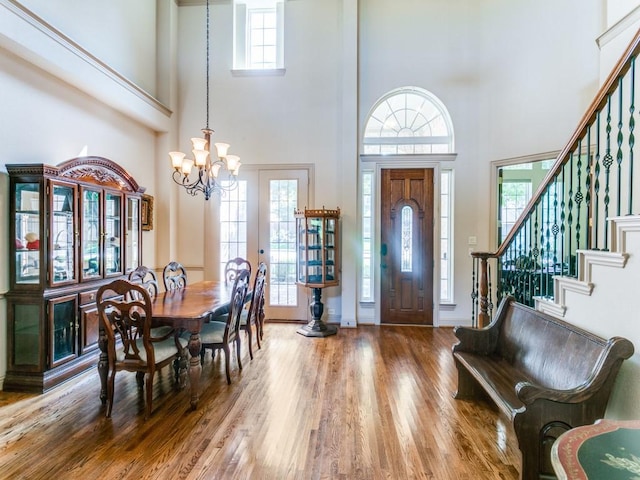 foyer featuring hardwood / wood-style floors, a notable chandelier, and a high ceiling