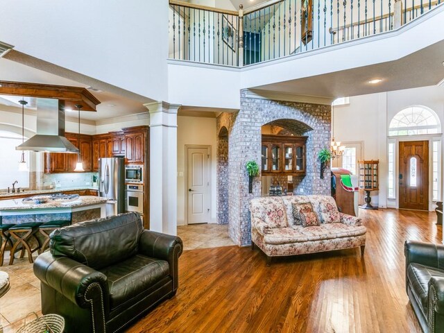 living room with a high ceiling, light wood-type flooring, ornamental molding, and sink