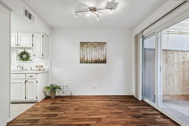 dining space featuring sink, dark wood-type flooring, and brick wall