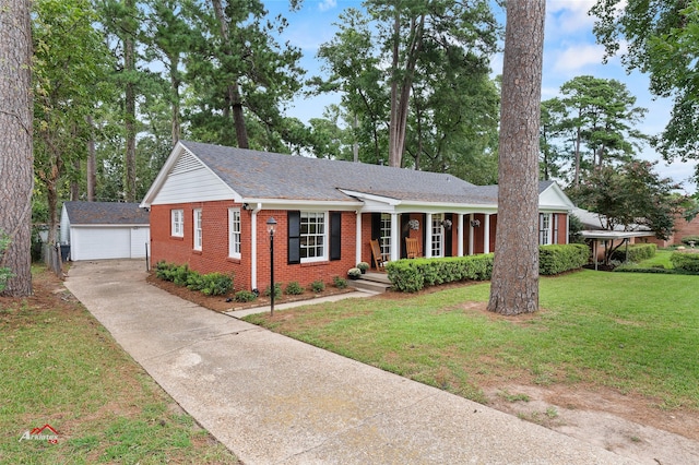 ranch-style home featuring a garage, a front lawn, covered porch, and an outbuilding