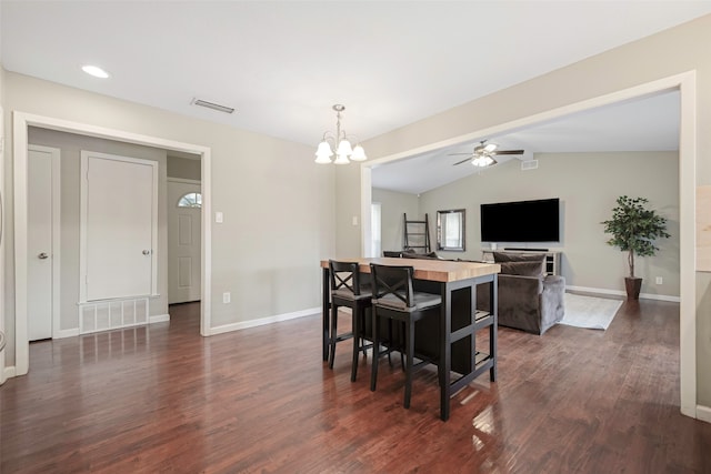 dining room featuring ceiling fan with notable chandelier, vaulted ceiling, and dark wood-type flooring