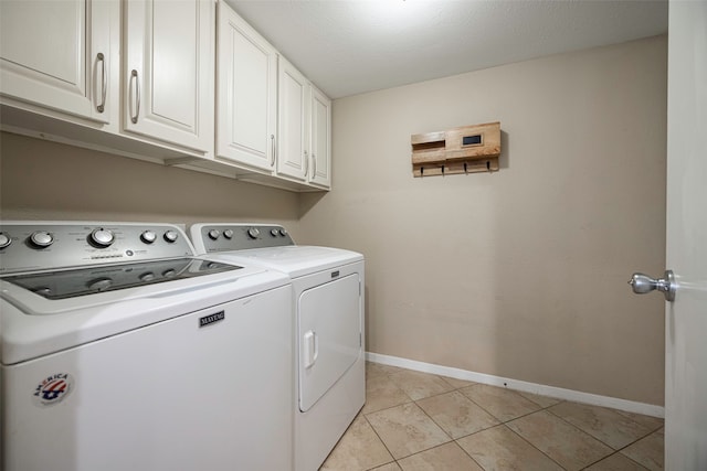 washroom featuring a textured ceiling, washer and clothes dryer, light tile patterned floors, and cabinets