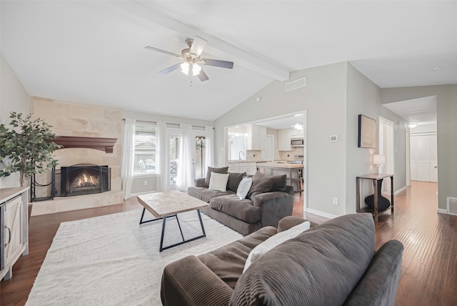 living room featuring vaulted ceiling with beams, dark wood-type flooring, ceiling fan, and a fireplace