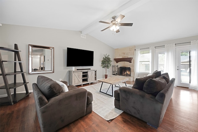 living room with vaulted ceiling with beams, a stone fireplace, dark hardwood / wood-style flooring, and ceiling fan