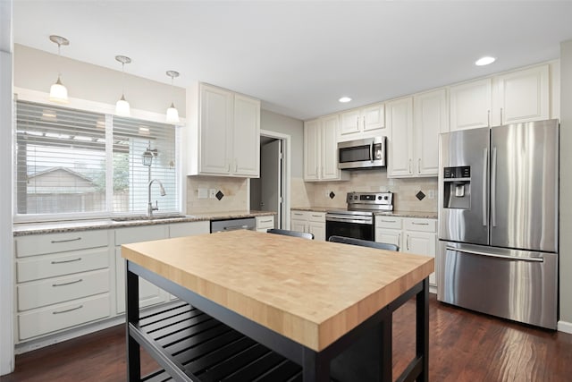 kitchen featuring appliances with stainless steel finishes, decorative backsplash, dark wood-type flooring, and white cabinets