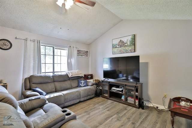 living room with light wood-type flooring, vaulted ceiling, ceiling fan, and a textured ceiling