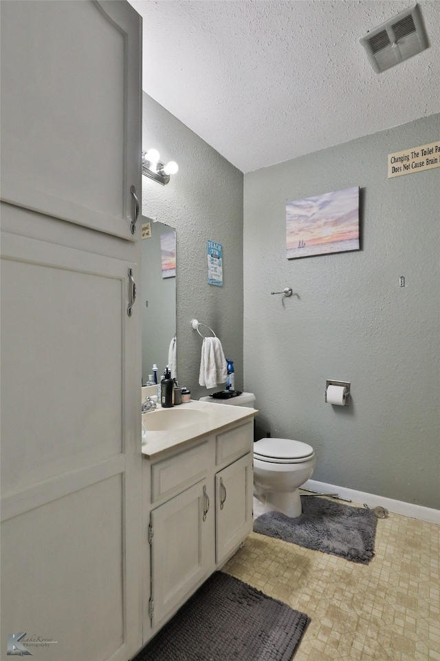 bathroom with vanity, toilet, and a textured ceiling