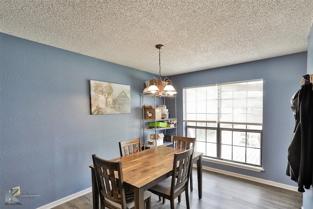 dining room featuring a notable chandelier, wood-type flooring, and a textured ceiling