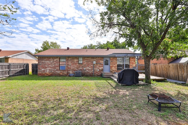 back of house with a lawn, central air condition unit, and a fire pit