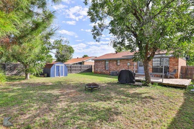 view of yard featuring a storage shed, a deck, central AC, and a fire pit