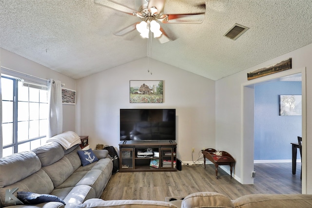 living room with lofted ceiling, light hardwood / wood-style floors, ceiling fan, and a textured ceiling