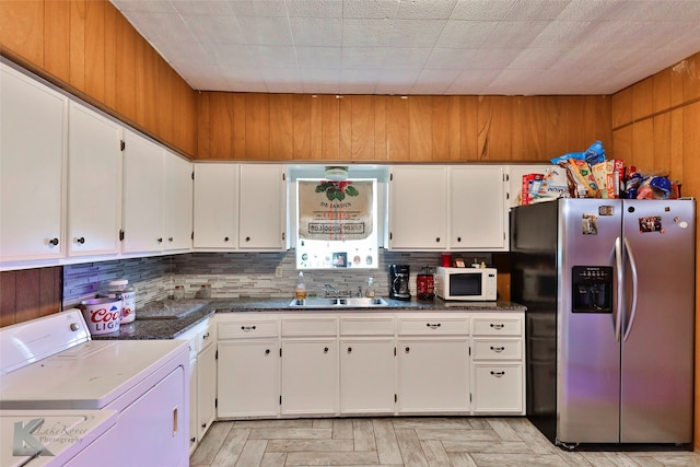 kitchen with washer / clothes dryer, stainless steel refrigerator with ice dispenser, backsplash, and white cabinets